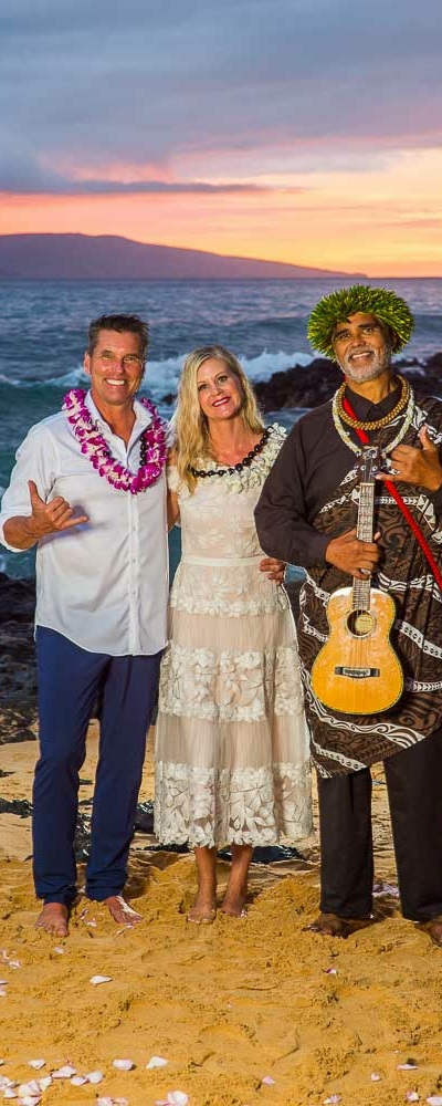 Happy Couple enjoying sunset with their minister after saying their vows on a beach in Maui