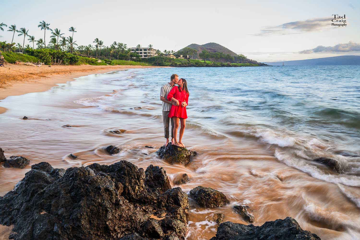 Just engaged couple laughing on rocks during a Maui Sunset
